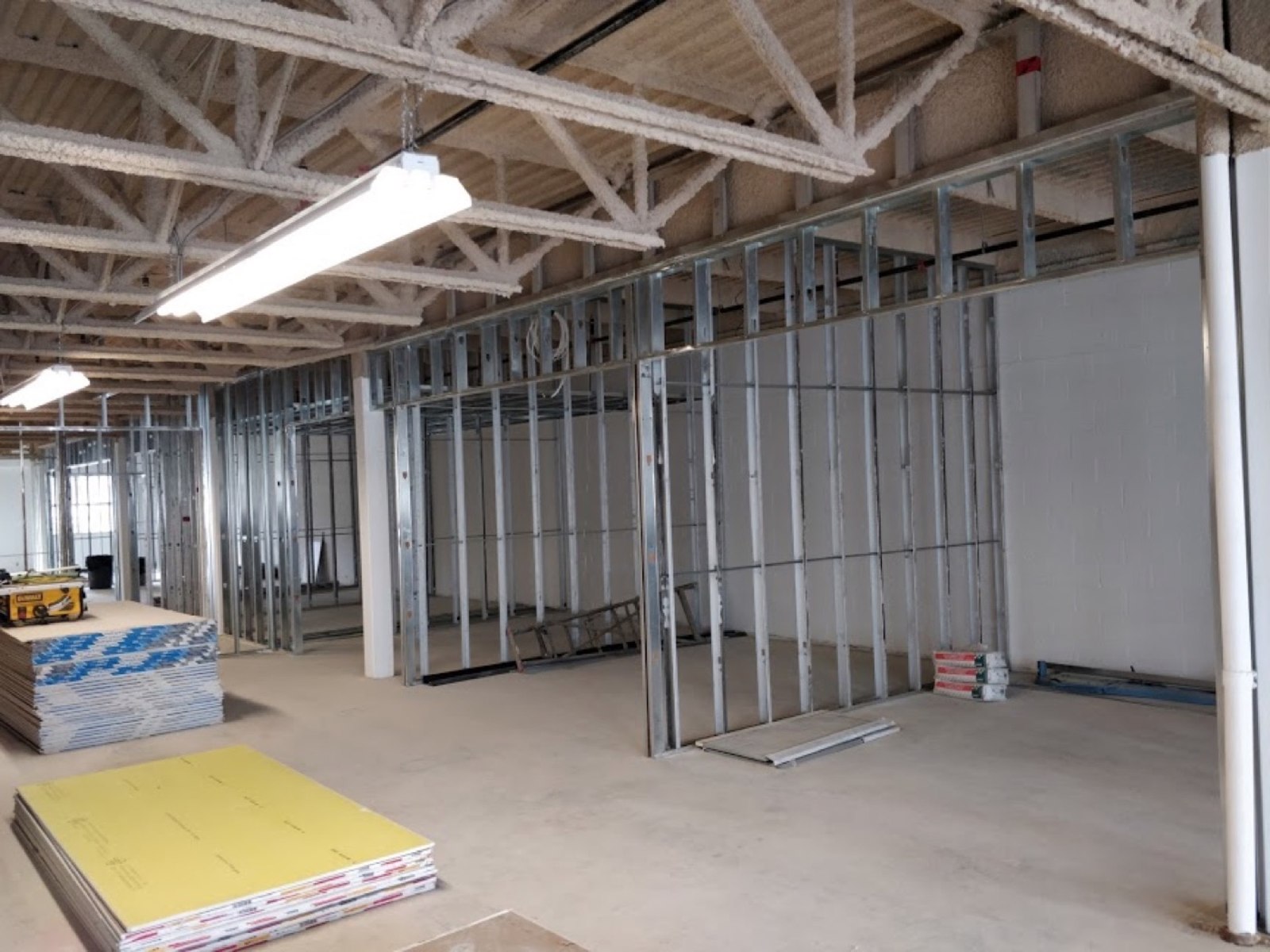Steel-stud partitions beneath exposed services during a commercial interior buildout
