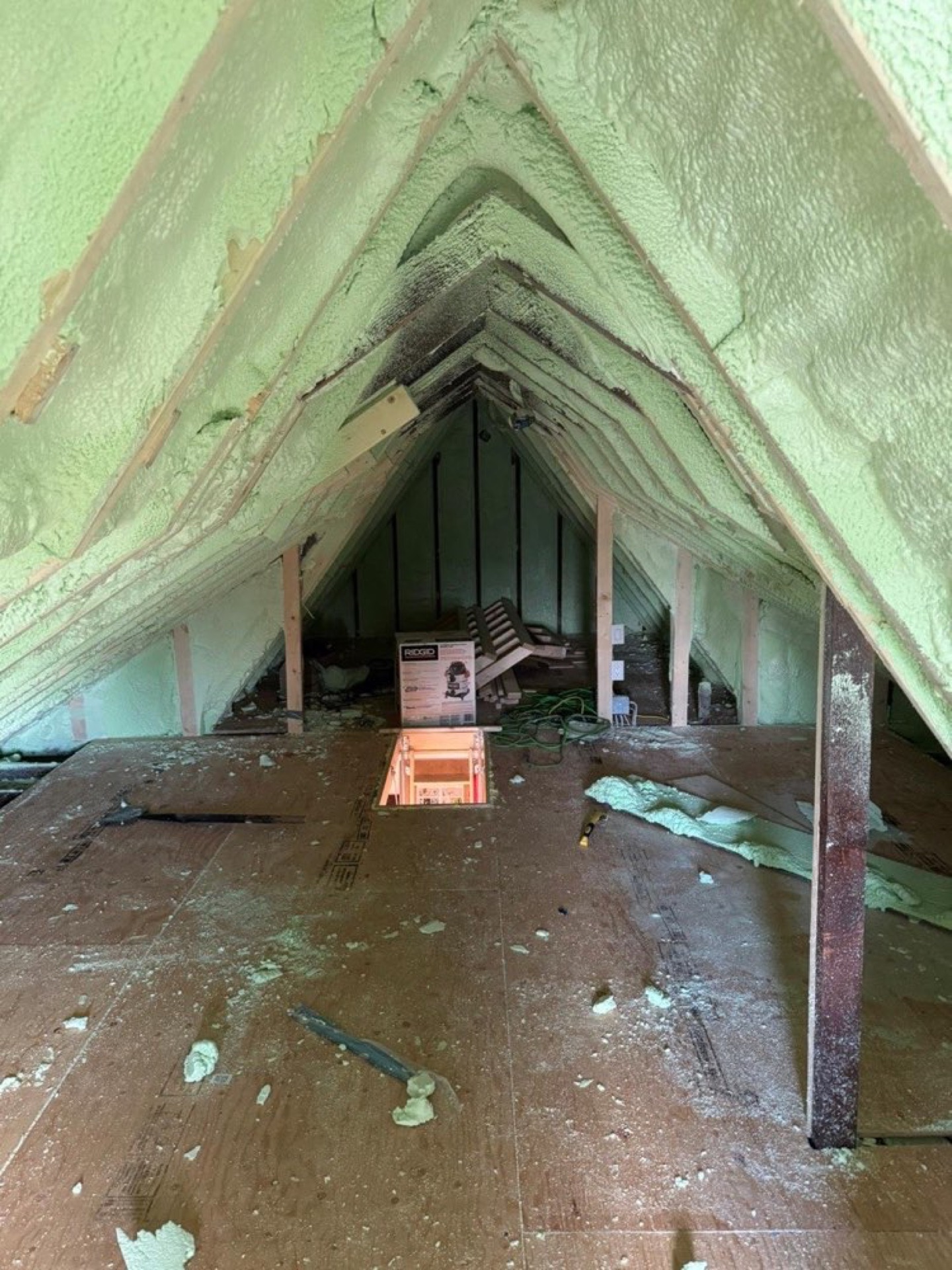 Green insulation along a sloped roofline with equipment in the work area